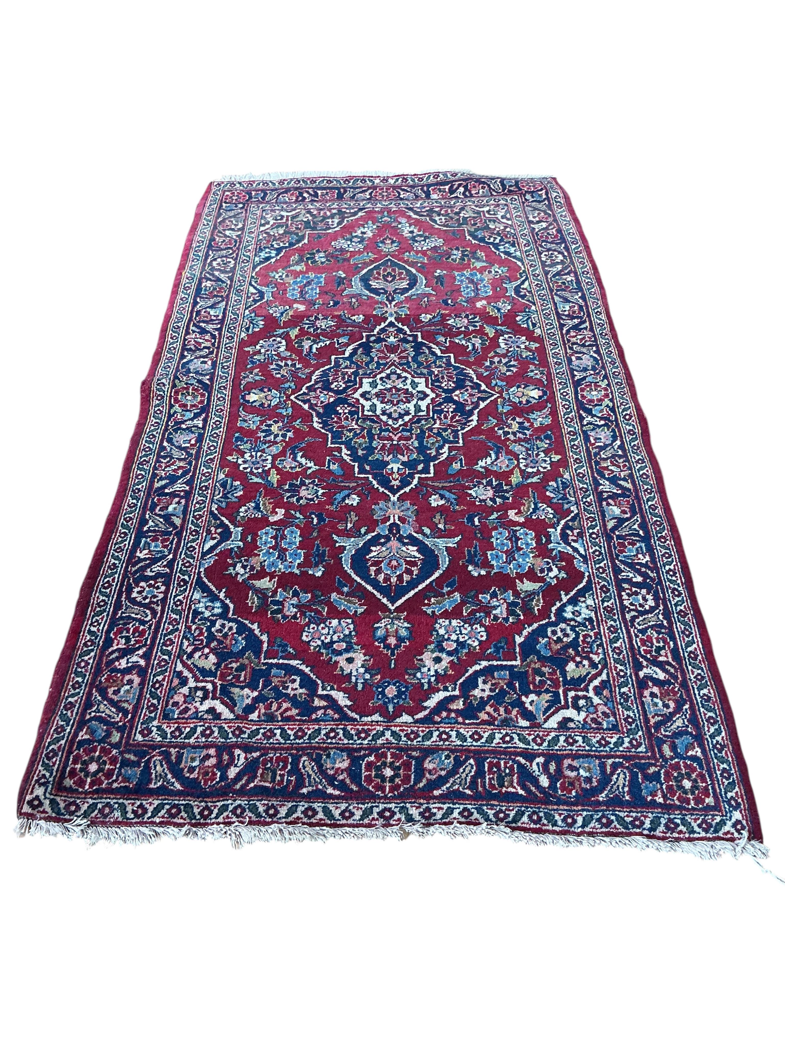 A North West Persian burgundy ground rug, 130 x 70cm